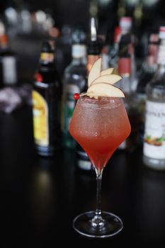 Pink Cocktail glass with ice at a bar counter