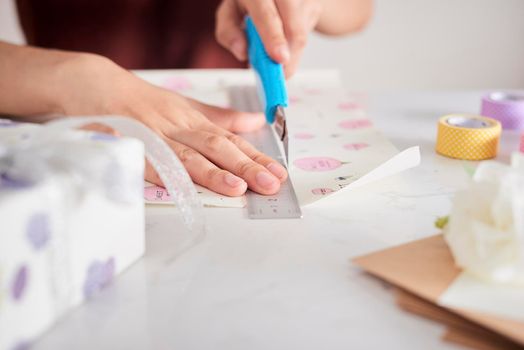 Detail of woman hands packing some presents with gift paper