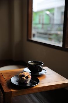 Coffee cup with muffin on wood table in local coffee shop