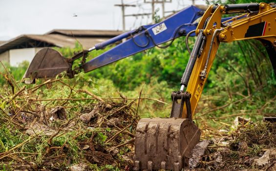 Backhoe digging soil at construction site. Bucket of backhoe digging soil. Clearing and grubbing. Digger working at road construction site. Earth moving machine. Excavation vehicle. Land development. 