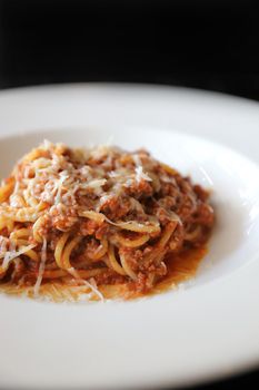 spaghetti Bolognese with minced beef and tomato sauce garnished with parmesan cheese and basil 