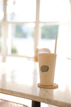 Iced coffee with paper glass in coffee shop background