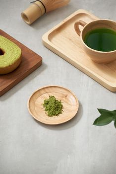 Green tea matcha in a wooden cup with German cake on the brown mat close-up