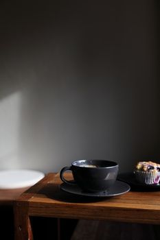Coffee cup with muffin on wood table in local coffee shop