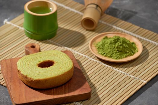 Matcha green tea latte in a cup and tea ceremony utensils with German cake. Copy space