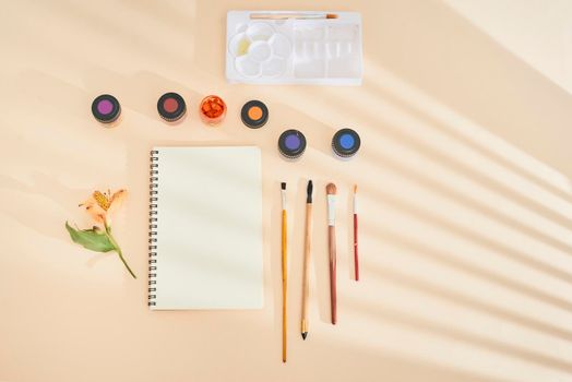 Set of watercolor paint, art brushes and paper on a desk 