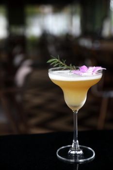 Yellow Cocktail glass with ice at a bar counter