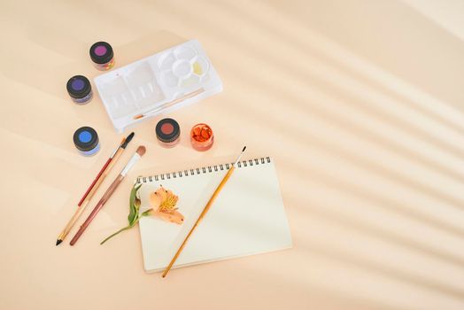 Set of watercolor paint, art brushes and paper on a desk 