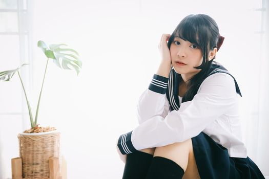 japanese school girl sitting on bedroom in white tone