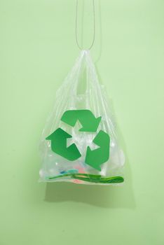 waste recycling, reuse, garbage disposal, environment and ecology concept - close up of rubbish bag with trash or garbage and green recycle symbol at home