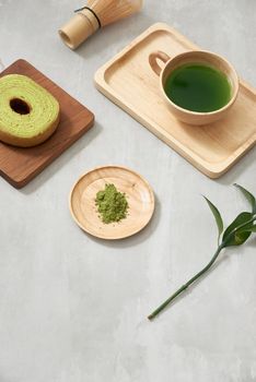 Matcha green tea latte in a cup and tea ceremony utensils with German cake. Copy space