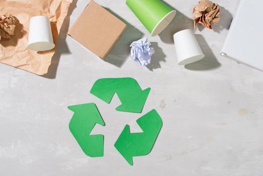 recycling symbol with waste on wooden background top view