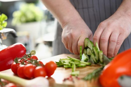 Green cucumbers are cut with knife in kitchen. Healthy food concept vegetable salad and vegetarianism