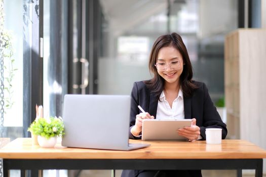 Portrait of young Asian business woman using digital tablet in the office..