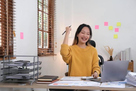 Pretty Asian businesswoman sitting on a laptop And the work came out successfully and the goal was achieved, happy and satisfied with her..