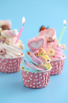 Colorful cupcakes with candle isolated in blue background