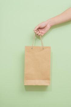 Woman holding paper shopping bag on green background