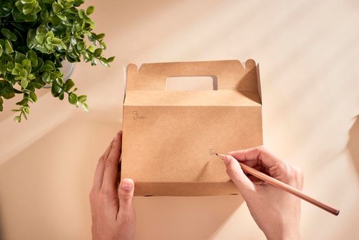 Cropped image of woman writing best wishes on box with present