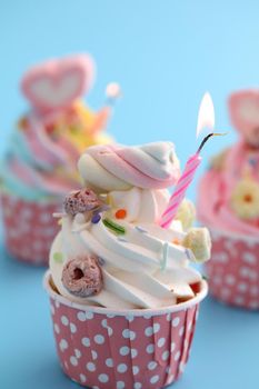 Colorful cupcakes with candle isolated in blue background