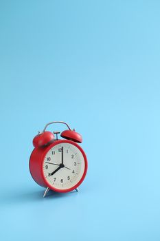 Red retro alarm clock isolated on a blue background
