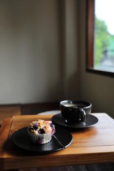 Coffee cup with muffin on wood table in local coffee shop