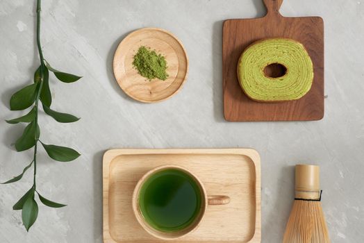 Green tea matcha in a wooden cup with German cake on the brown mat close-up