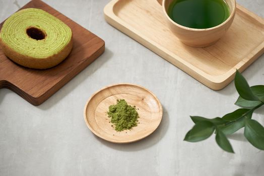 Green tea matcha in a wooden cup with German cake on the brown mat close-up