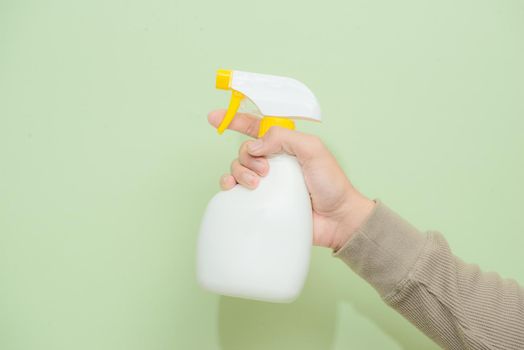 Male hand with sprayer isolated on green background