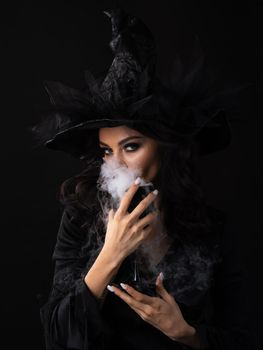 Halloween party woman in witch costume holding goblet of potion drink with smoke
