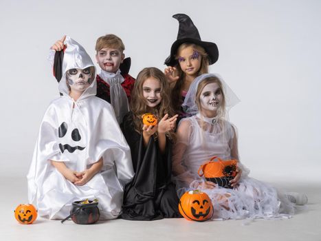 Group of children in costumes holding sweets at Halloween party