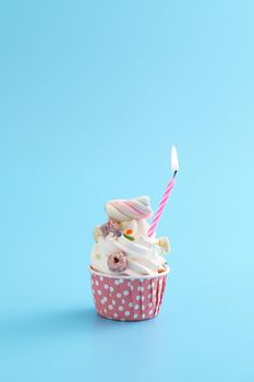 Colorful cupcake with candle isolated in blue background