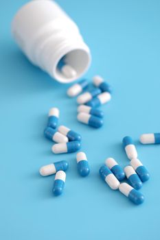 pills capsules with bottle isolated on blue background