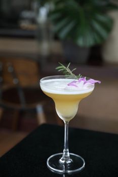 Yellow Cocktail glass with ice at a bar counter