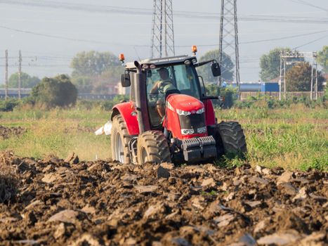4k video of red tractor plowing the land in the countryside.