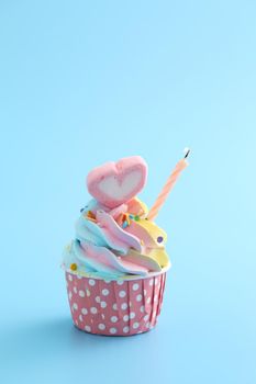 Colorful cupcake with candle isolated in blue background