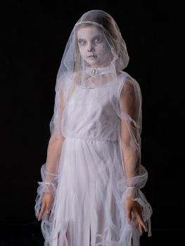 Little girl in Halloween ghost costume looking at camera, studio isolated on black background