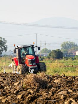 4k video of red tractor plowing the land in the countryside.