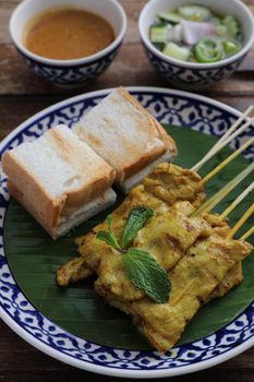 Local Thai food pork satay with oeanut dipping sauce isolated in wood background