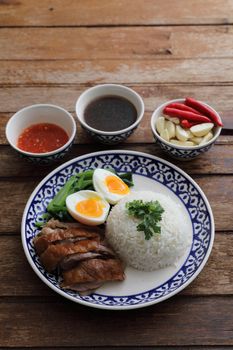 Local Thai food stewed pork leg on rice isolated in wood background
