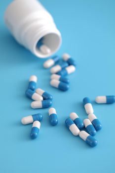 pills capsules with bottle isolated on blue background