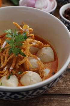 Local northern Thai food Egg noodle curry with meatballs on wood background