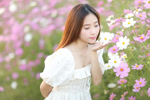 Beautiful young woman with white dress on pink cosmos flowers background