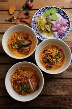 Local northern Thai food Egg noodle curry with pork and beef on wood background