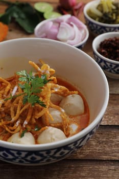 Local northern Thai food Egg noodle curry with meatballs on wood background