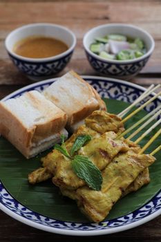 Local Thai food pork satay with oeanut dipping sauce isolated in wood background