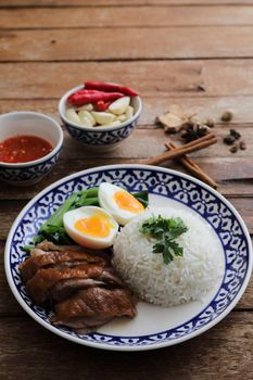 Local Thai food stewed pork leg on rice isolated in wood background
