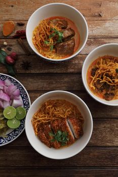 Local northern Thai food Egg noodle curry with pork and beef on wood background