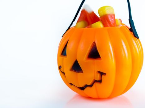 Halloween treat bag filled with candy corn candies on white background.