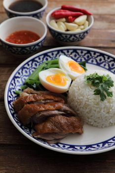 Local Thai food stewed pork leg on rice isolated in wood background
