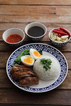 Local Thai food stewed pork leg on rice isolated in wood background
